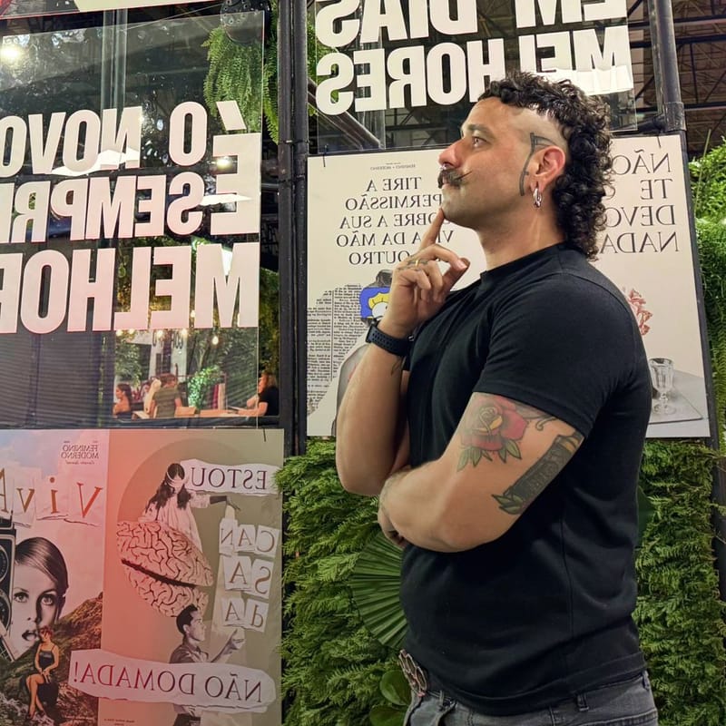 Nil diante de uma parede de cartazes tipográficos do Feminino Moderno