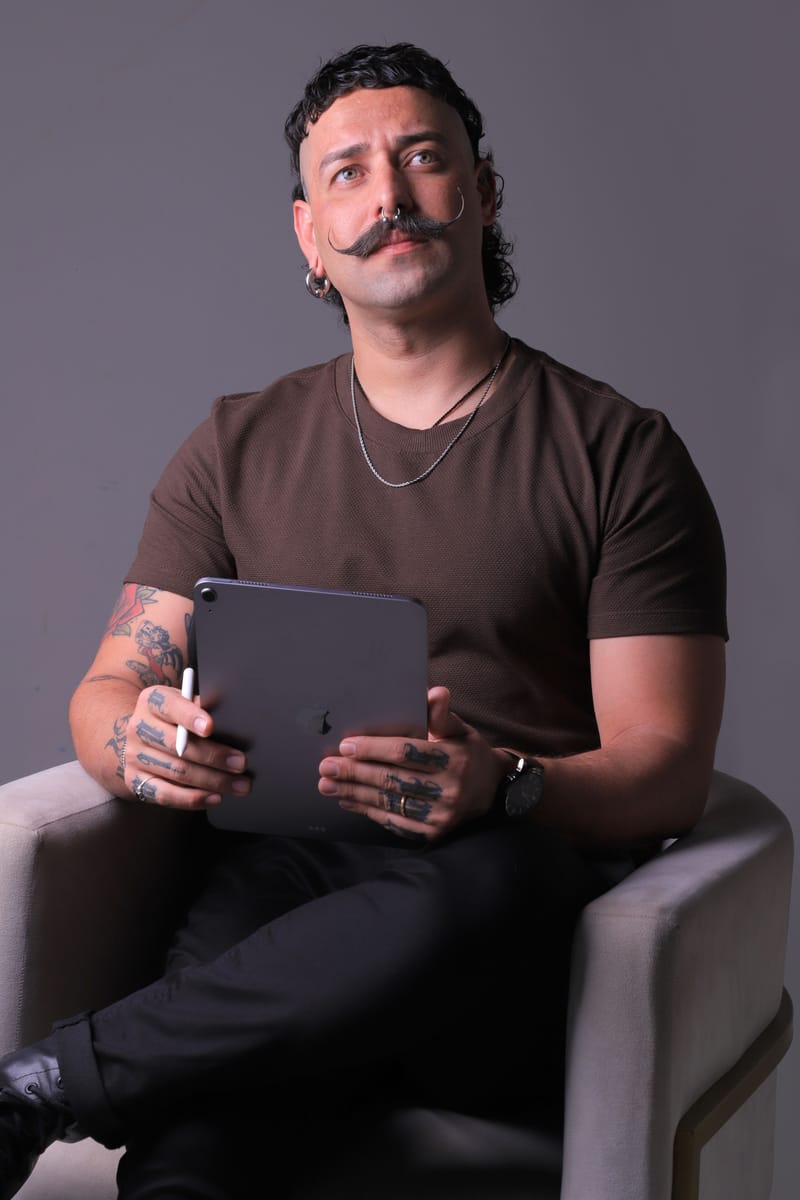 Retrato em preto e branco de Nil, Diretor Criativo do Studio Pixel Rain, sentado, com um tablet nas mãos e o olhar para cima